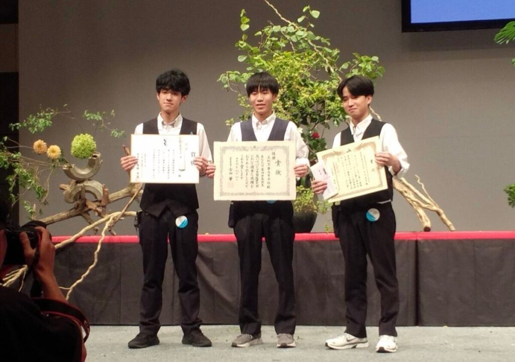 表彰後に賞状と3人